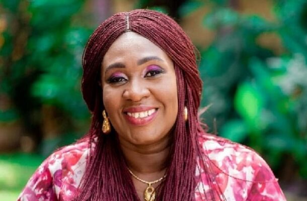 no_translation_7567_e0cy2fufqun7bgm01pwyz9lm_no_translation_translation | Ghanaguardian.com Portrait of a smiling woman with burgundy braids, gold earrings and necklace, wearing a pink floral top outdoors.