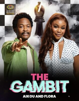 Poster for 'The Gambit' featuring Aikou and Flora: a man in a green jacket points toward the camera beside a woman in a white polka-dot blouse. A large chess king looms behind them amid a black-and-white checkered background; bold pink and teal title 'THE GAMBIT' with smaller text 'Aikou and Flora'.